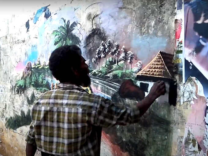 Artista di strada senzatetto indiano che usa colori naturali per mentre  dipinge un murales nello stato indano del Kerala